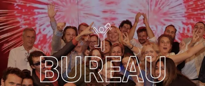 Group celebration photo of advertising professionals holding "Bureau van het jaar" (Agency of the Year) award with overlaid text of the same name.